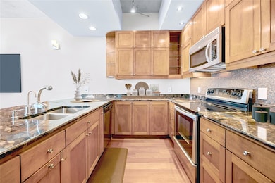 Kitchen with dark stone counters, stainless steel