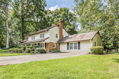 Traditional home with driveway, a chimney, and a f