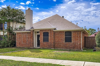 Ranch-style house featuring brick siding, a shingled roof, and a chimney
