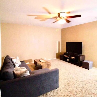 Carpeted living room with ceiling fan