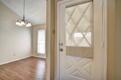 Doorway to outside featuring a textured ceiling, wood finished floors, and a textured wall