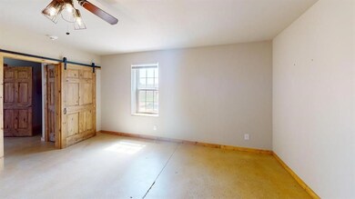 Unfurnished bedroom featuring a barn door and base