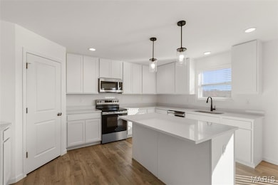 Kitchen with appliances with stainless steel finishes, white cabinetry, pendant lighting, dark wood-type flooring, and recessed lighting
