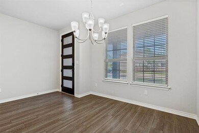 Spare room with a chandelier, dark wood-style flo