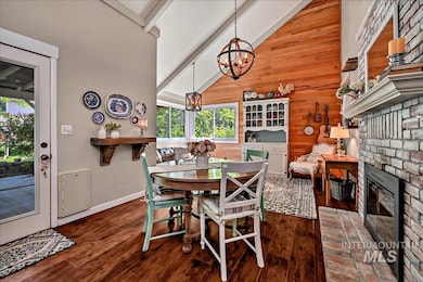 Dining room with a chandelier, wood finished floors, beamed ceiling, wooden walls, and high vaulted ceiling