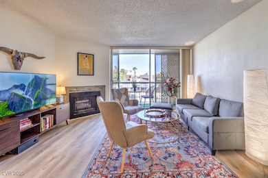 Living area featuring floor to ceiling windows, a fireplace, a textured ceiling, and light wood-style floors