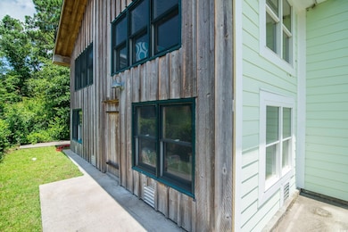View of home's exterior with board and batten siding, a patio, and a yard