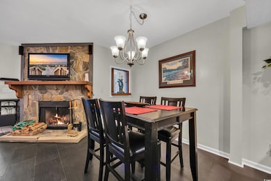 Dining room featuring a chandelier, wood finished floors, baseboards, and a stone fireplace