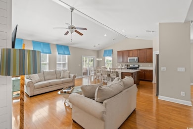 Living room with light wood finished floors, lofted ceiling, ceiling fan, a chandelier, and recessed lighting
