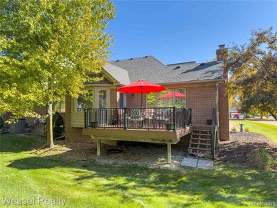 Back of property with a wooden deck, a shingled roof, a lawn, brick siding, and a chimney