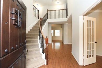 Front door entry opens to reveal an elegant curved staircase, wood flooring and soaring ceilings.