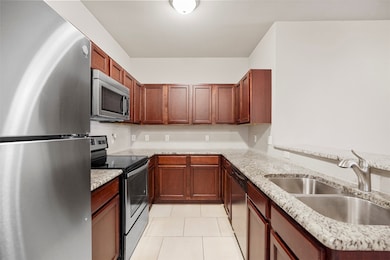 Kitchen featuring stainless steel appliances, light stone countertops, and light tile patterned floors