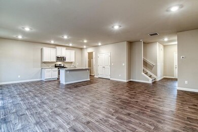 Kitchen featuring stainless steel appliances, open floor plan, dark wood finished floors, recessed lighting, and white cabinetry