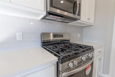 Kitchen with backsplash, white cabinetry, and appl