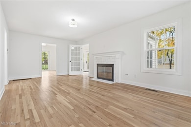 Unfurnished living room featuring  tons of natural light, light wood flooring, and a tiled fireplace