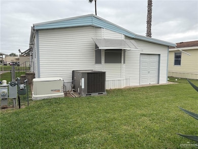 Rear view of house with a garage, central AC unit, and a lawn