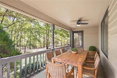Virtually staged sunroom featuring a ceiling fan, outdoor dining area, and view of wooded area