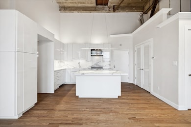 Modern kitchen with sleek white cabinetry, a central island, and stainless-steel appliances. Double doors pictured right, utility room