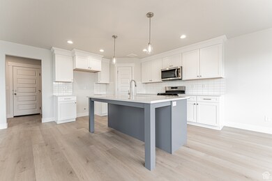Kitchen featuring white cabinets, stainless steel appliances, and light wood-style flooring