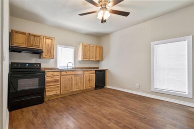 Kitchen with dark hardwood / wood-style flooring, black appliances, and ceiling fan