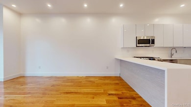 Kitchen featuring recessed lighting, modern cabinets, light wood-type flooring, a peninsula, and stainless steel microwave