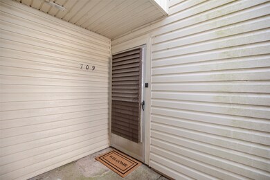 Covered entryway with beige siding and a storm doo