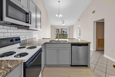Kitchen with gray cabinets, stainless steel appliances, a peninsula, tasteful backsplash, and high vaulted ceiling