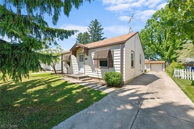 Bungalow with a garage, a front lawn, and an outdoor structure