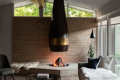 Living room with plenty of natural light, lofted ceiling, brick wall, and a fireplace