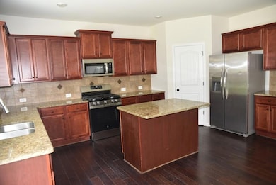 Kitchen with appliances with stainless steel finishes, dark brown cabinets, and dark wood finished floors