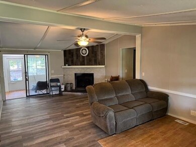 Living area featuring wood finished floors, a ceiling fan, a fireplace, and vaulted ceiling
