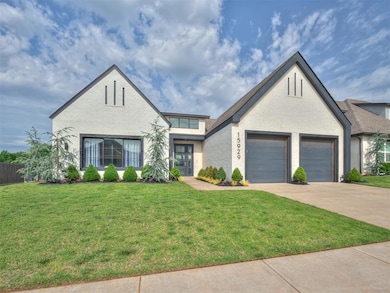 View of front of home with driveway, brick siding, a front lawn, french doors, and a garage