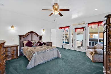 Primary bedroom featuring dark carpet, access to wrap around porch, and large windows.