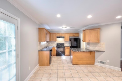 Kitchen with tasteful backsplash, ornamental molding, black appliances, a breakfast bar, and dark stone counters