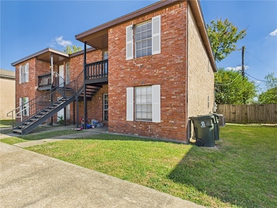 Back of house featuring stairway, brick siding, and a lawn
