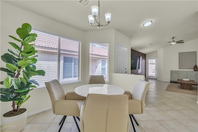 Dining space with light tile patterned flooring, lofted ceiling, ceiling fan, and a chandelier