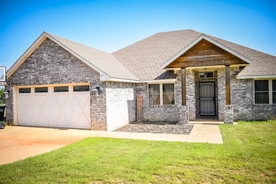 View of front of property featuring a garage, a shingled roof, a front yard, and brick siding