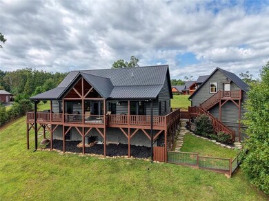 Rear view of house featuring stairs, a deck, a lawn, and a metal roof
