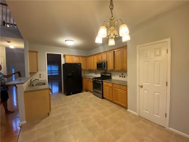 Kitchen featuring stainless steel appliances, a chandelier, pendant lighting, and a peninsula