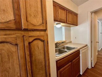 Kitchen with white dishwasher, brown cabinetry, da