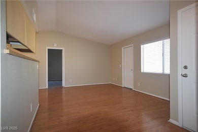 Empty room featuring baseboards, vaulted ceiling,