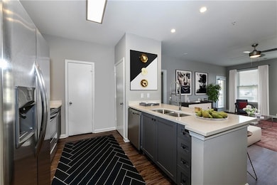 Kitchen featuring appliances with stainless steel finishes, a peninsula, light countertops, open floor plan, and dark wood finished floors