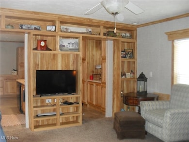Carpeted living room with ceiling fan and ornamental molding