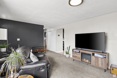 Living area featuring light carpet and a glass covered fireplace