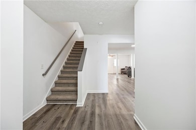 Stairs featuring a textured ceiling and wood-type flooring