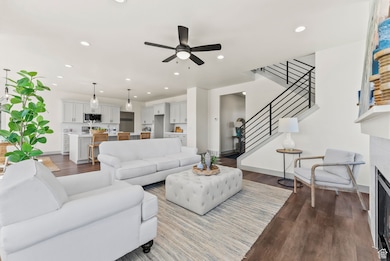 Living area featuring dark wood-style flooring, recessed lighting, stairs, a fireplace, and ceiling fan