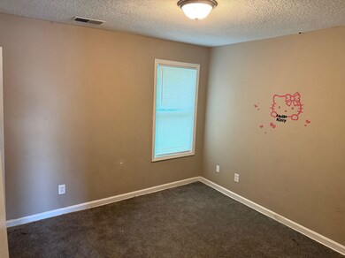 Spare room featuring a textured ceiling and dark carpet