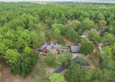 In this aerial view, the log home is truly the centerpiece of this 5 acres. The pond, building/workshop, greenhouse, gardening shed, and raised garden beds all add a touch of uniqueness and functionality to the property. It is a place where you can truly enjoy nature.