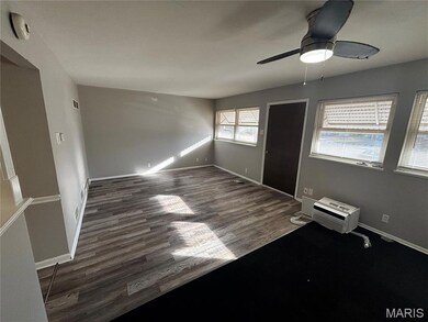 Unfurnished bedroom featuring dark wood-style flooring, a ceiling fan, and an AC wall unit