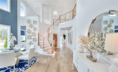 Entrance foyer featuring light wood finished floors, a high ceiling, recessed lighting, a chandelier, and stairs